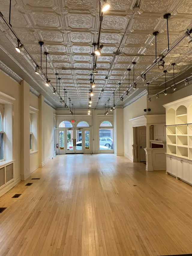 The long studio hall with a pressed-tin ceiling, track lights and arched front windows